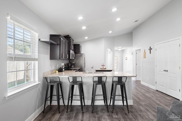 kitchen with a peninsula, range, freestanding refrigerator, and a healthy amount of sunlight