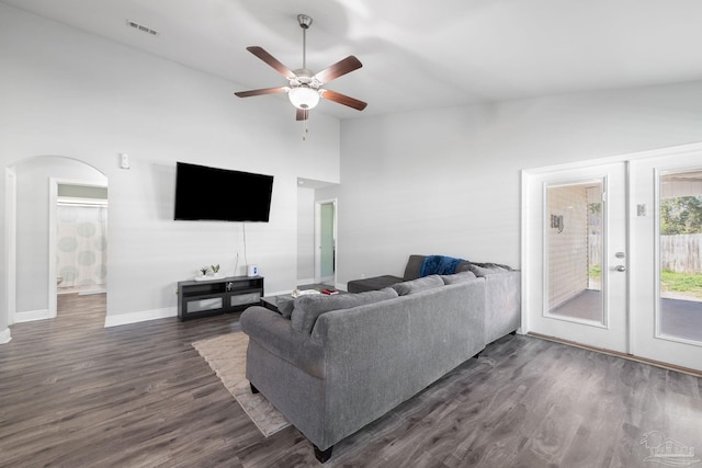 living area featuring dark wood-style floors, baseboards, visible vents, high vaulted ceiling, and arched walkways