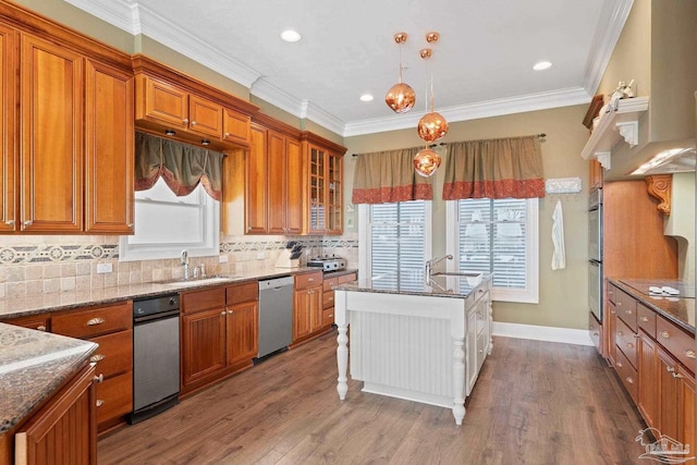 kitchen with hanging light fixtures, glass insert cabinets, brown cabinetry, appliances with stainless steel finishes, and a sink