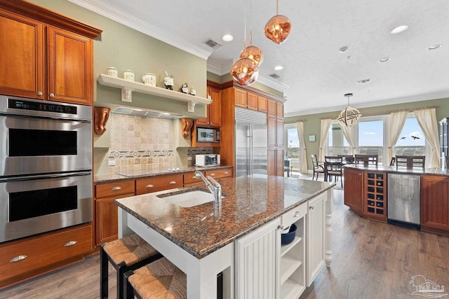 kitchen with a breakfast bar, pendant lighting, open shelves, and built in appliances