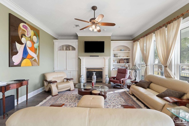 living room featuring dark wood-style floors, crown molding, visible vents, a glass covered fireplace, and baseboards