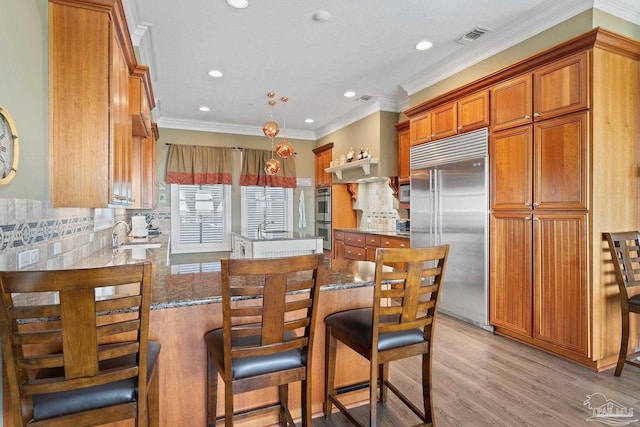 kitchen featuring brown cabinets, dark stone counters, and stainless steel appliances