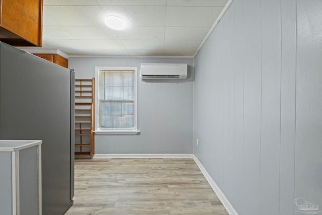 interior space featuring an AC wall unit, light wood-style flooring, baseboards, and ornamental molding