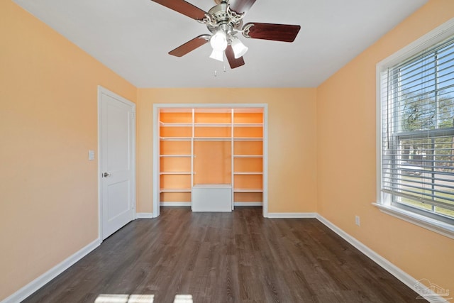 unfurnished bedroom with a closet, baseboards, dark wood-type flooring, and a ceiling fan