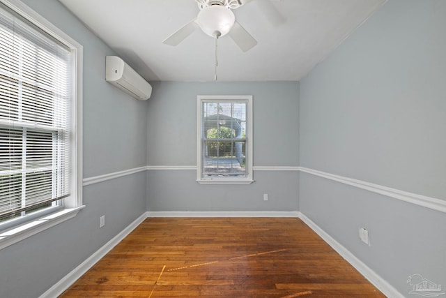 spare room featuring a wall mounted air conditioner, baseboards, wood finished floors, and a ceiling fan