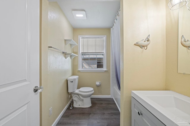 bathroom with baseboards, toilet, shower / bath combo, wood finished floors, and vanity