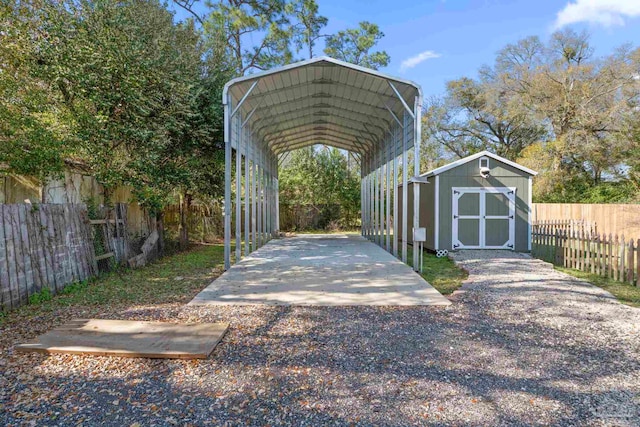 view of vehicle parking featuring a detached carport, a shed, gravel driveway, and fence