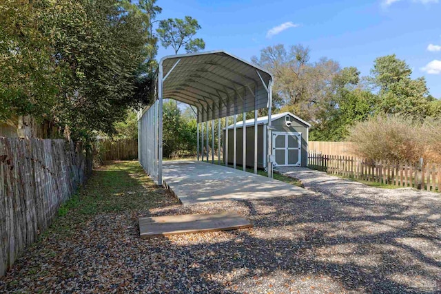 view of parking / parking lot with a carport, gravel driveway, fence private yard, and a shed