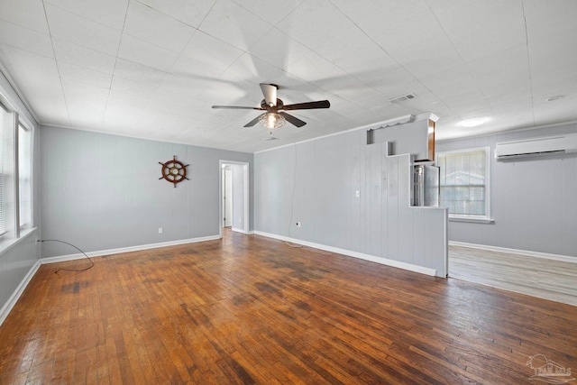 unfurnished room featuring visible vents, an AC wall unit, ceiling fan, and hardwood / wood-style flooring