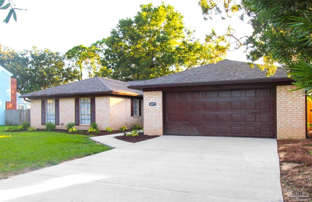 ranch-style home featuring an attached garage, driveway, a front lawn, and brick siding