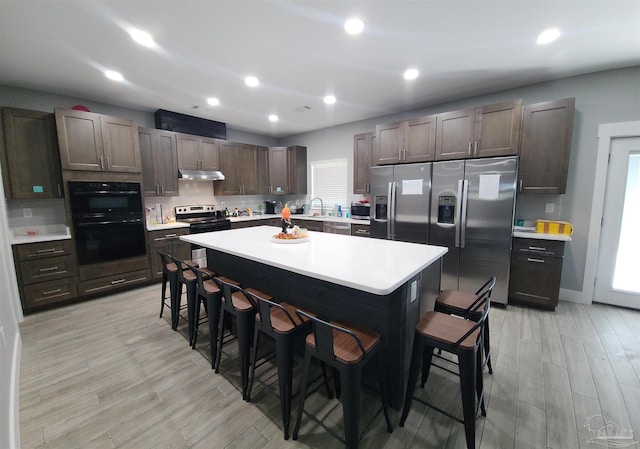 kitchen featuring a kitchen breakfast bar, a center island, stainless steel appliances, and light wood-type flooring