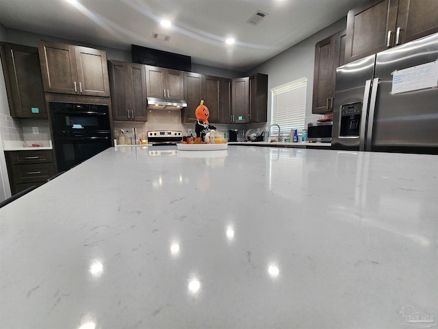 kitchen featuring decorative backsplash, dark brown cabinetry, stainless steel appliances, and sink