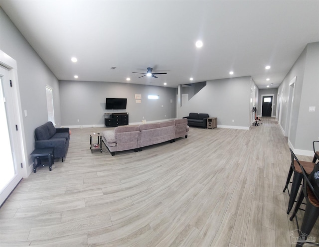 living room with ceiling fan and light wood-type flooring