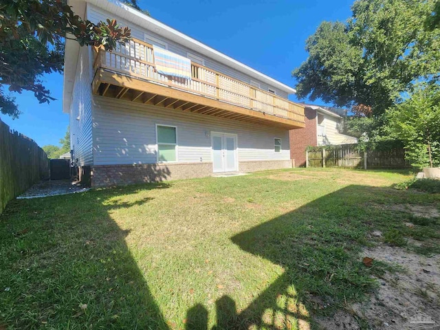 rear view of house with a lawn and a balcony