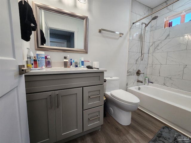 full bathroom featuring hardwood / wood-style floors, vanity, tiled shower / bath combo, and toilet