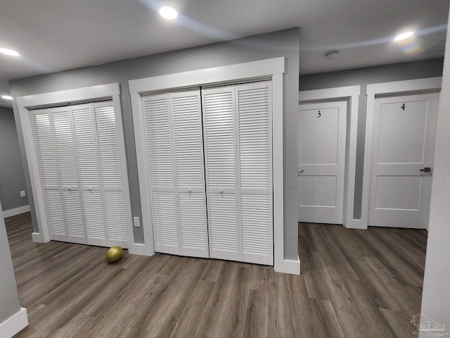 unfurnished bedroom featuring two closets and dark wood-type flooring