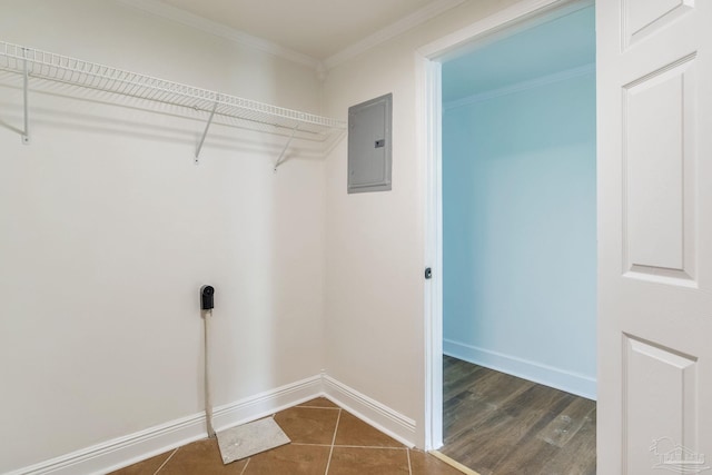 laundry area featuring ornamental molding, electric panel, and dark tile patterned flooring