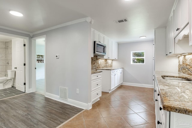 kitchen featuring light stone counters, sink, backsplash, and white cabinets