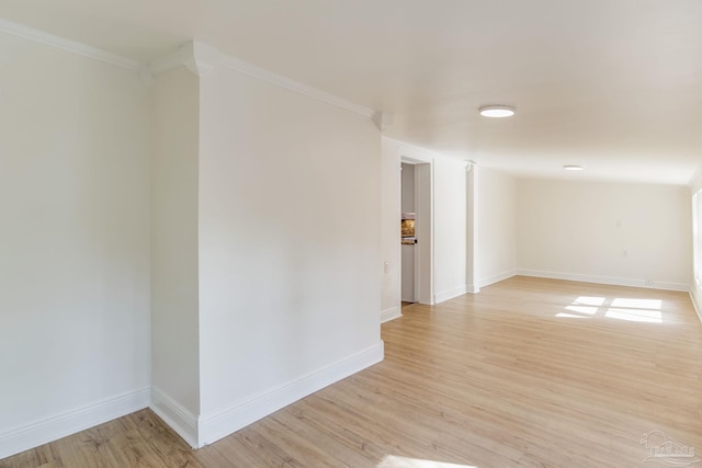 empty room featuring crown molding and light wood-type flooring