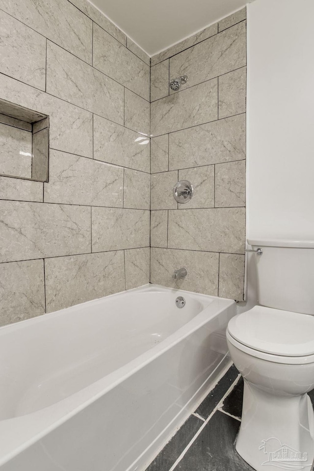 bathroom with toilet and tiled shower / bath