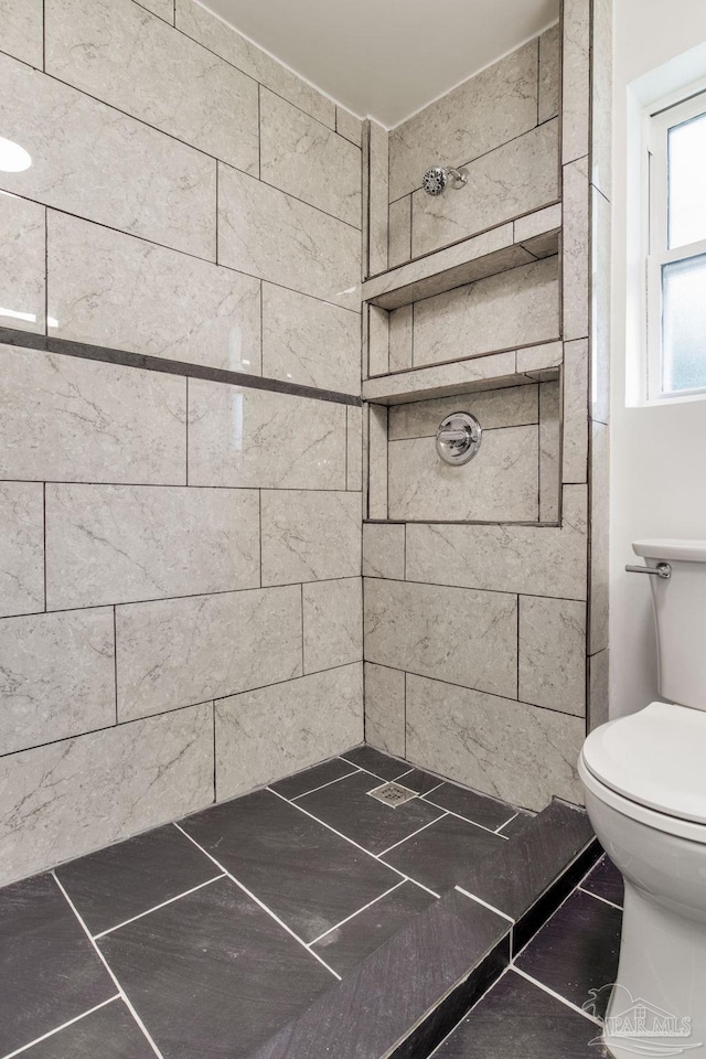 bathroom featuring a tile shower and toilet