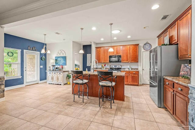 5409 Dalton Cir, Milton, FL 32570 - kitchen featuring stainless steel appliances, brown cabinetry, light tile patterned floors, a breakfast bar, and an island with sink