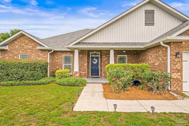 5409 Dalton Cir, Milton, FL 32570 - view of front of house featuring board and batten siding, a porch, roof with shingles, a front lawn, and brick siding
