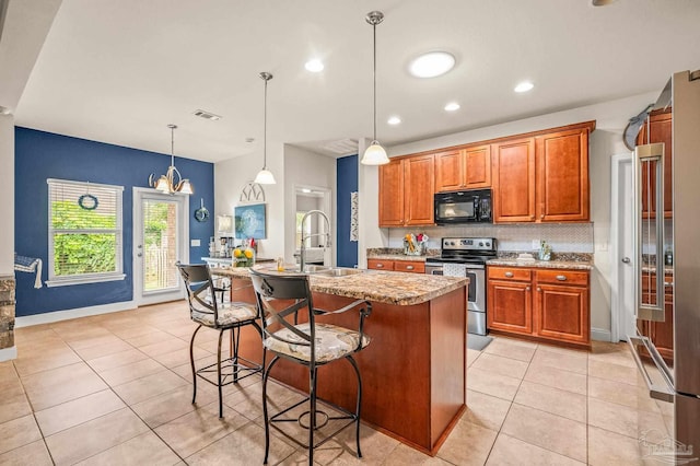 5409 Dalton Cir, Milton, FL 32570 - kitchen with stainless steel appliances, light tile patterned floors, decorative backsplash, brown cabinets, and an island with sink