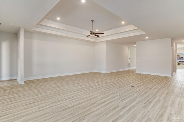 spare room with light wood-style floors, a raised ceiling, and ornamental molding