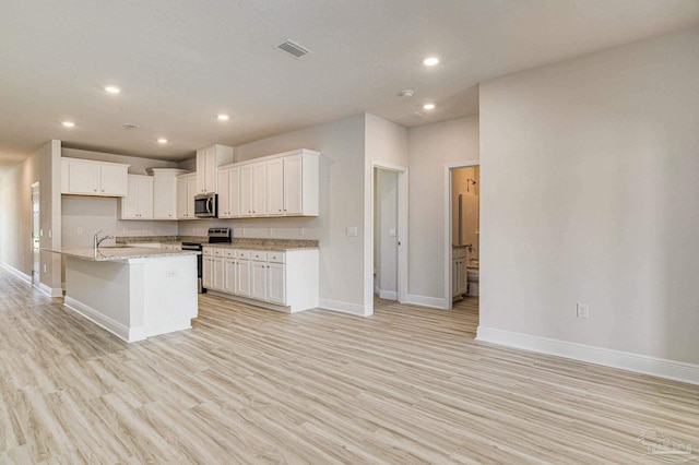 kitchen with recessed lighting, light wood-style flooring, appliances with stainless steel finishes, white cabinets, and baseboards