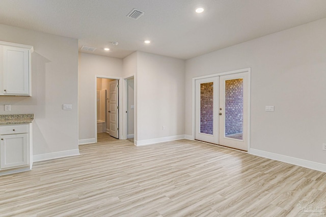 unfurnished room with light wood-style flooring, visible vents, baseboards, and french doors