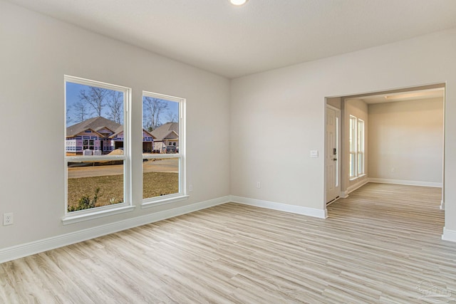 empty room with light wood finished floors, baseboards, and a wealth of natural light