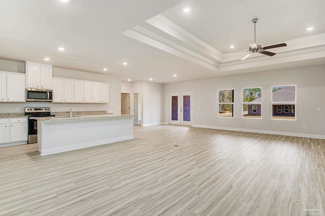 kitchen featuring a tray ceiling, stainless steel appliances, french doors, and open floor plan