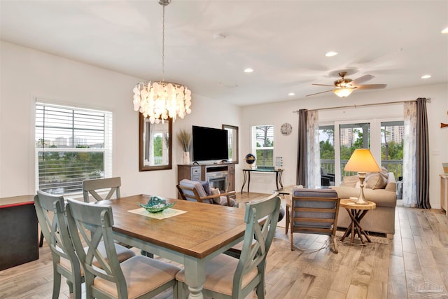 dining space featuring ceiling fan with notable chandelier and light hardwood / wood-style flooring