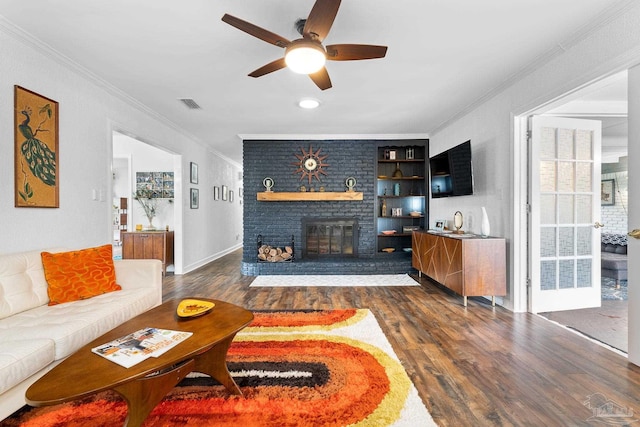 living area featuring visible vents, dark wood-style floors, ceiling fan, crown molding, and a fireplace