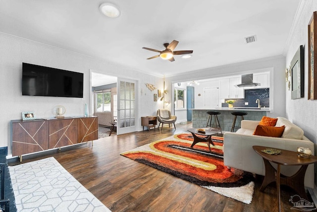 living room featuring ornamental molding, dark wood finished floors, and ceiling fan