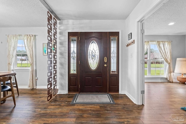 foyer with a textured ceiling, dark wood finished floors, and baseboards