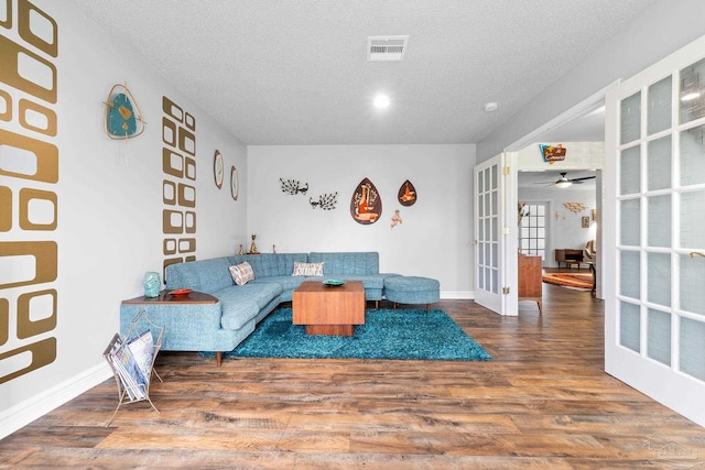 living area with a textured ceiling, french doors, wood finished floors, and visible vents