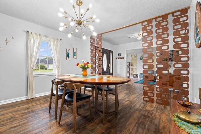 dining space featuring dark wood-type flooring, a notable chandelier, a textured ceiling, and baseboards