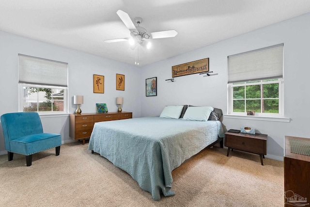 bedroom with ceiling fan, baseboards, and light colored carpet