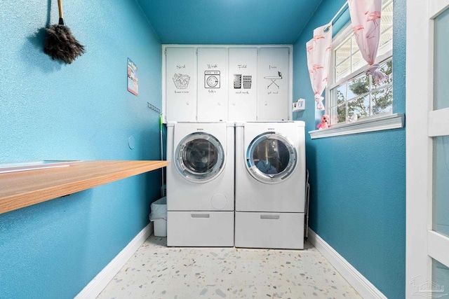 washroom featuring a textured wall, laundry area, washing machine and clothes dryer, and baseboards