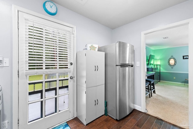 kitchen with dark wood-style floors, freestanding refrigerator, visible vents, and baseboards