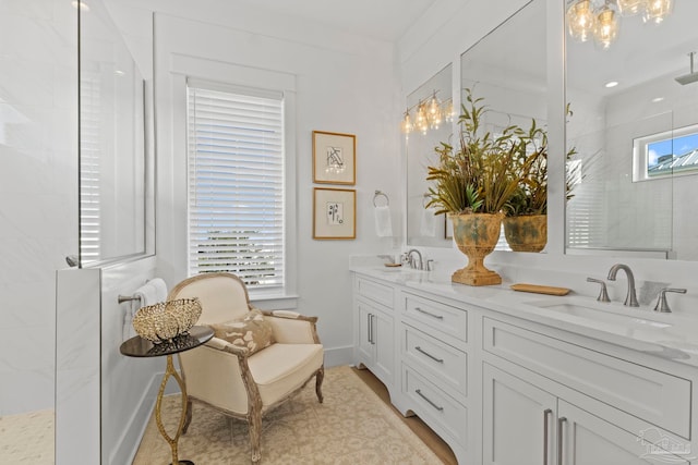 bathroom featuring a sink, baseboards, double vanity, and a walk in shower