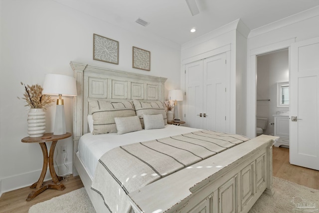 bedroom featuring visible vents, ensuite bath, ornamental molding, light wood-style floors, and a closet