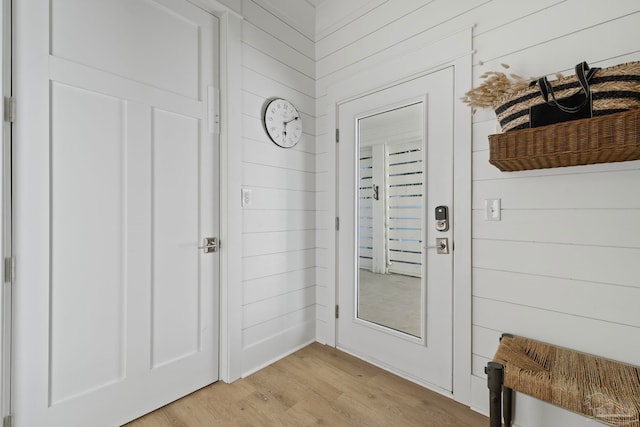 entryway featuring light wood-type flooring and wood walls