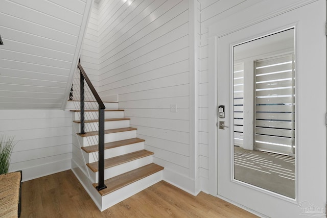 stairway with lofted ceiling, wooden walls, wood finished floors, and a sauna