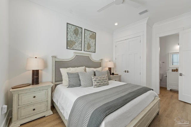 bedroom featuring visible vents, ornamental molding, light wood-style flooring, ensuite bathroom, and a closet