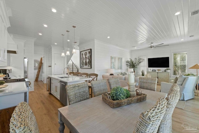 dining area featuring light wood finished floors, stairs, ornamental molding, ceiling fan with notable chandelier, and wooden ceiling