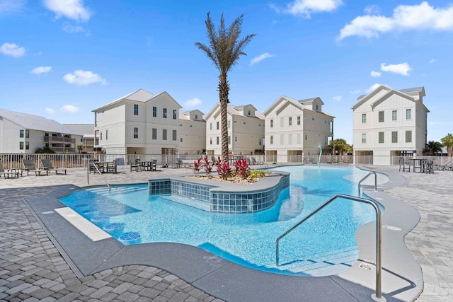 community pool with a patio area, a residential view, and fence