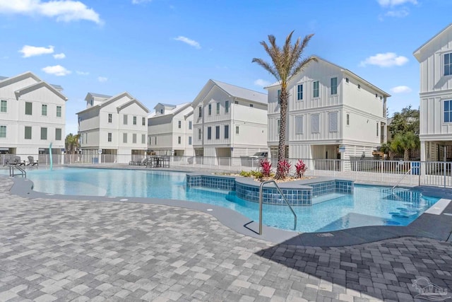 pool with a patio area, fence, and a residential view